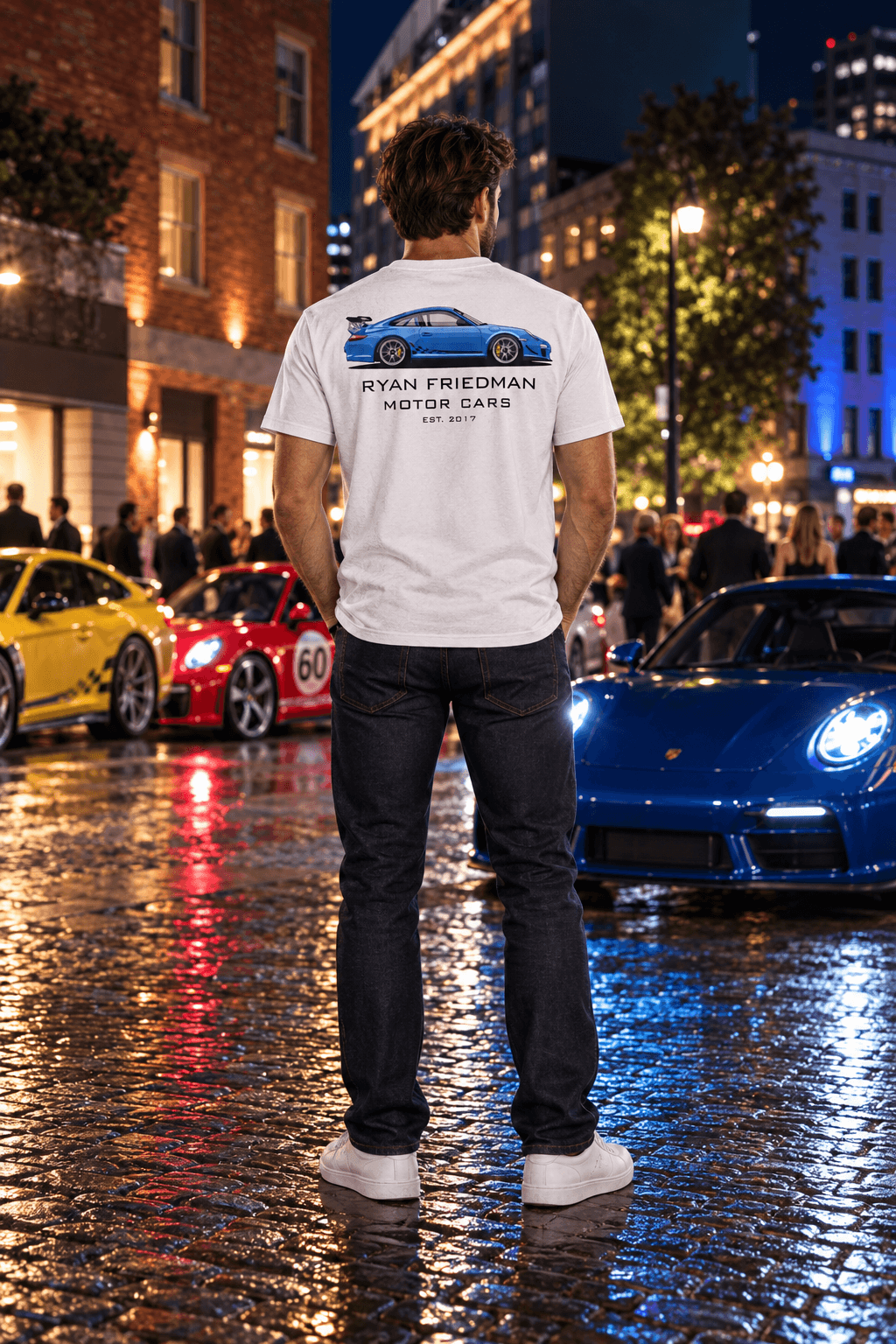 Man wearing the Blue GT3 RS T-Shirt from behind, showing the back print, at a night car meet on a wet cobblestone street
